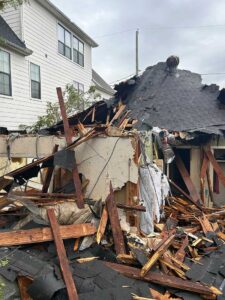 Collapsed house with debris and roof damage.