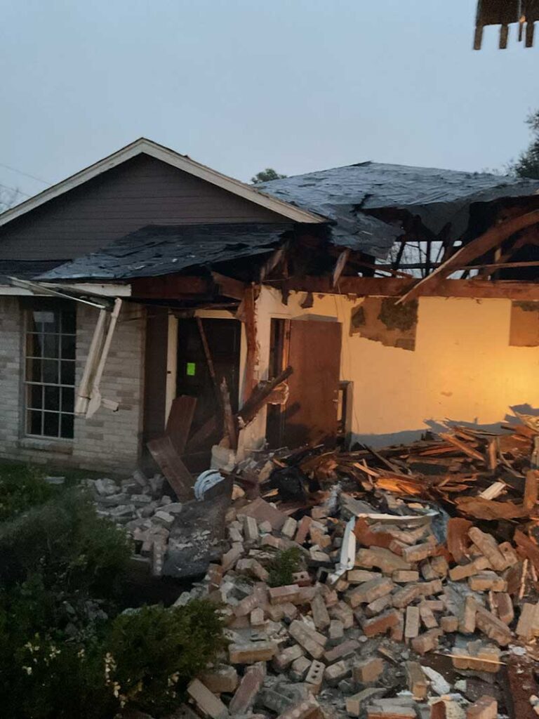 Partially collapsed house with debris and bricks.